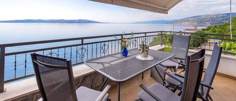 Una terrazza con tavolo, sedie e vista su uno specchio d'acqua e montagne in lontananza.
