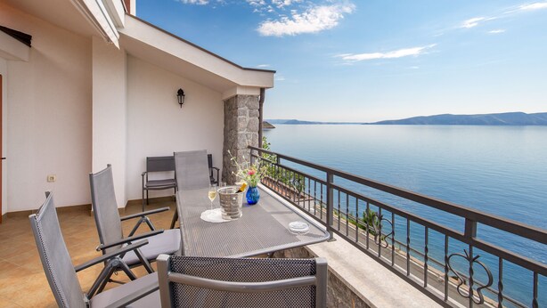 Un balcon avec une table et des chaises donnant sur une étendue d’eau.