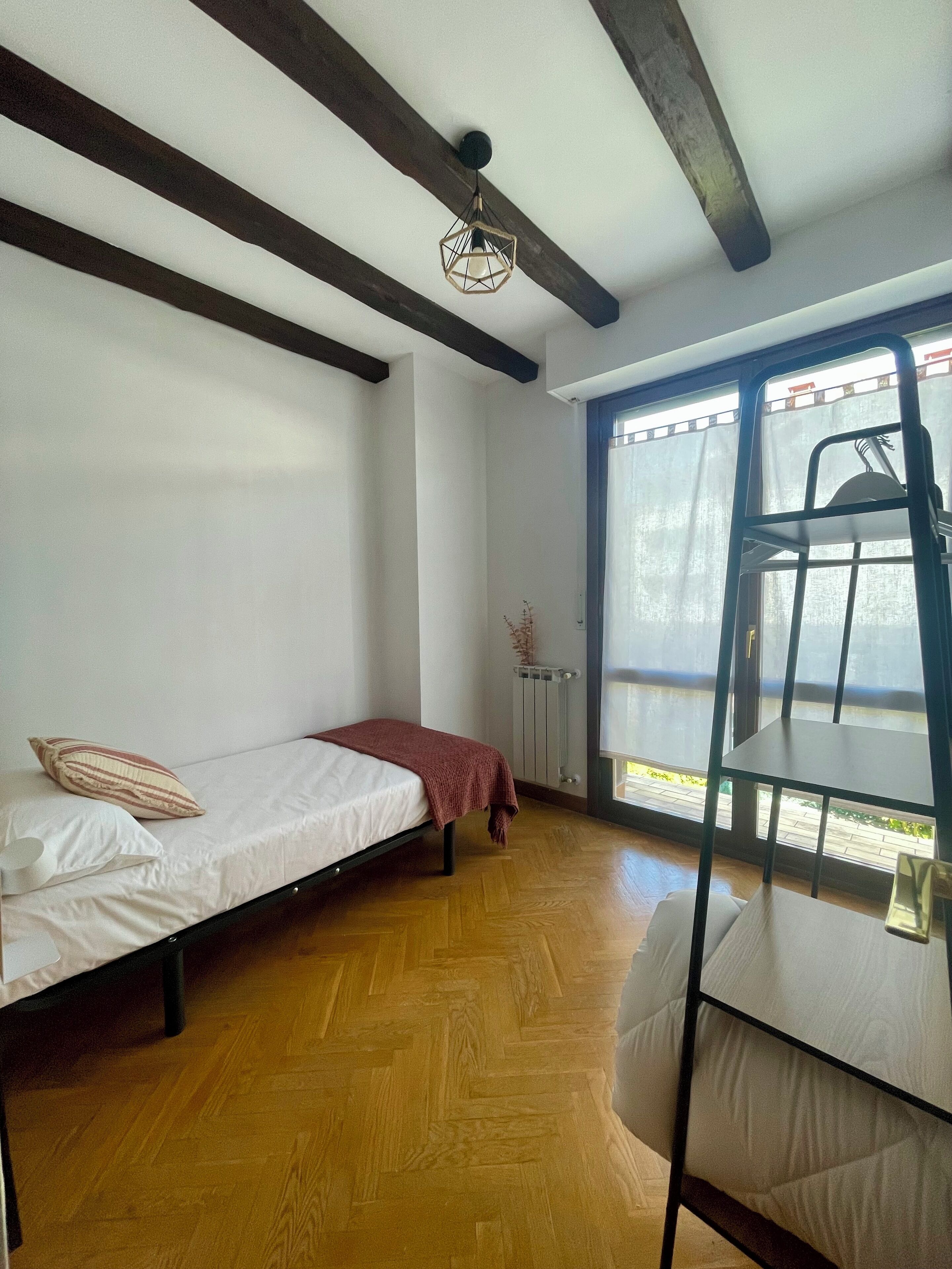Ein Zimmer mit Bett, Stuhl und Fenster.