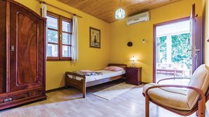 Un dormitorio con cama de madera, una silla, armario, ventana con cortinas y puerta que da al exterior.