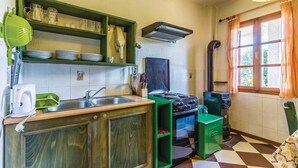 Una cocina pequeña con un lavamanos, estufa y armarios verdes.