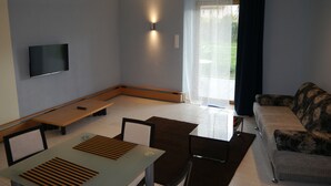 Una sala de estar moderna con un sofá, una mesa de comedor y un televisor en la pared.