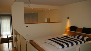 Un dormitorio moderno con cama, mesita de noche, espejo y ventana.
