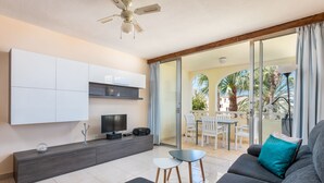 A modern living room with a sofa, TV, and a balcony with outdoor furniture. - Family-friendly apartment 4 people. near sea and pool (Callao Salvaje)
