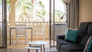 A living room with a sofa, a small table, and two chairs. There is a balcony with a view of palm trees. - Family-friendly apartment 4 people. near sea and pool (Callao Salvaje)
