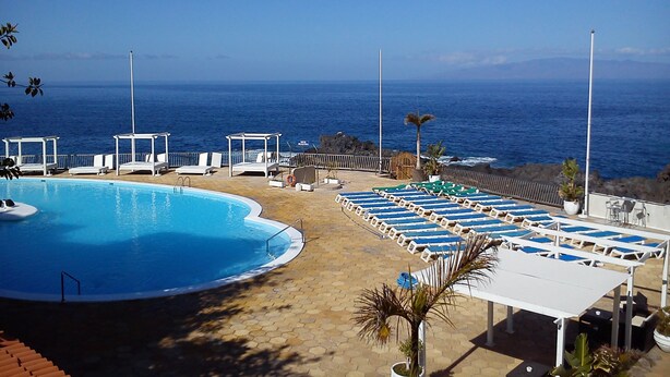 A pool area with lounge chairs and a view of the ocean. - Family-friendly apartment 4 people. near sea and pool (Callao Salvaje)
