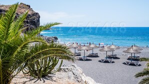 A beach with thatched umbrellas and lounge chairs, rocky cliffs, and a clear blue sea. - Family-friendly apartment 4 people. near sea and pool (Callao Salvaje)