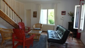 A living room with a staircase, a sofa, two armchairs, a coffee table, and a window with curtains. - quiet house on the banks of the Dordogne near Saint Emilion (Sainte-Terre)