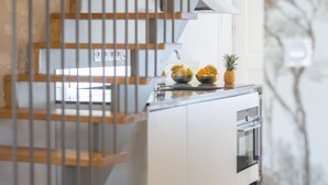 Eine Küche mit modernem Design, inklusive einer Arbeitsplatte aus Edelstahl, einem eingebauten Ofen und einer Schüssel mit Obst auf der Arbeitsfläche.