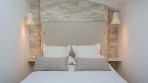 Ein modernes Schlafzimmer mit einem Kopfende im Stein-Look, zwei Nachttischen und zwei Lampen.
