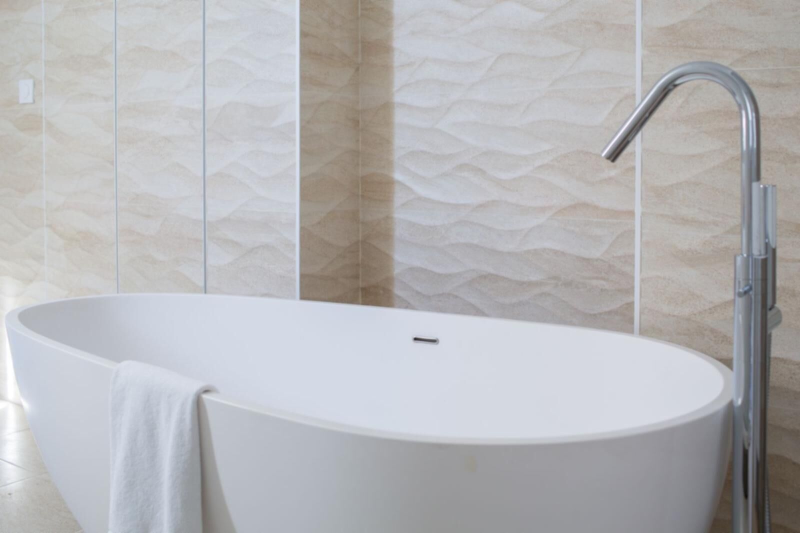 Une salle de bain moderne avec une baignoire sur pieds, un robinet chromé et des carreaux de mur à motifs.