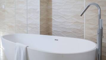 Une salle de bain moderne avec une baignoire sur pieds, un robinet chromé et des carreaux de mur à motifs.