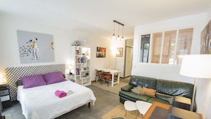 Een moderne hotelkamer met een bed, een groene bank, een eettafel en een bureau.