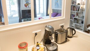 Een keuken met een groot raam, een koffiezetapparaat, een broodrooster en een waterkoker op het aanrecht.