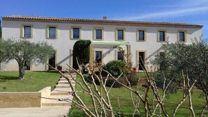 Un bâtiment à deux étages, doté d’un toit recouvert de tuiles, de nombreuses fenêtres et d’un auvent vert au-dessus de l’entrée.