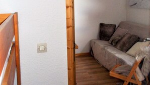 Una habitación con estructura de cama de madera, un sofá y una obra de arte colgada en la pared.