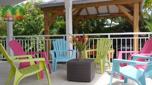 A covered outdoor seating area with colorful chairs and a central table. - LA VILLA DES VOYAGEURS WITH POOL AND SPA FOR 4 TO 12 PEOPLE (SAINT FRANCOIS)