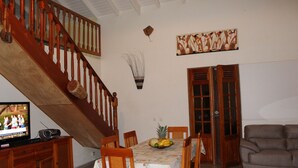 A dining area with a wooden table, chairs, a television, and a staircase. - LA VILLA DES VOYAGEURS WITH POOL AND SPA FOR 4 TO 12 PEOPLE (SAINT FRANCOIS)