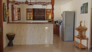 A kitchen with a marble island, wooden cabinets, a refrigerator, and a decorative item on a small table. - LA VILLA DES VOYAGEURS WITH POOL AND SPA FOR 4 TO 12 PEOPLE (SAINT FRANCOIS)