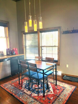 A dining area with a table, chairs, a rug, and hanging pendant lights. - 2-Bedroom apartment w/Loft (D7), walk to Main St. (Lake Placid)