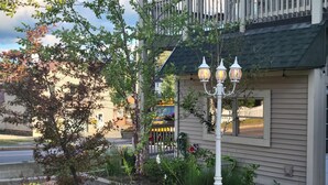 Un immeuble résidentiel doté d’un jardin aménagé, d’un lampadaire et d’un véhicule stationné dans l’allée.