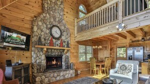 Un interior de cabaña acogedor con chimenea de piedra, mobiliario de madera y un comedor.