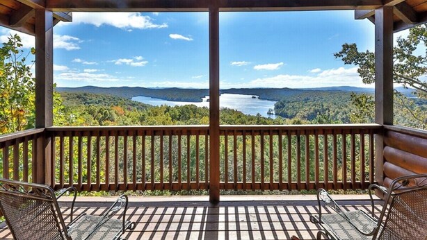 Una terraza de madera con vista a un lago y montañas.