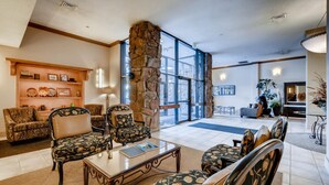 A spacious lobby with a stone pillar, comfortable seating, a coffee table, and a bookshelf. - Furnished 35th Floor Condo In The Heart Of Downtown Denver (Denver)