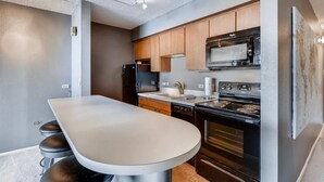 A modern kitchen with a central island, stainless steel appliances, and wooden cabinets. - Furnished 35th Floor Condo In The Heart Of Downtown Denver (Denver)