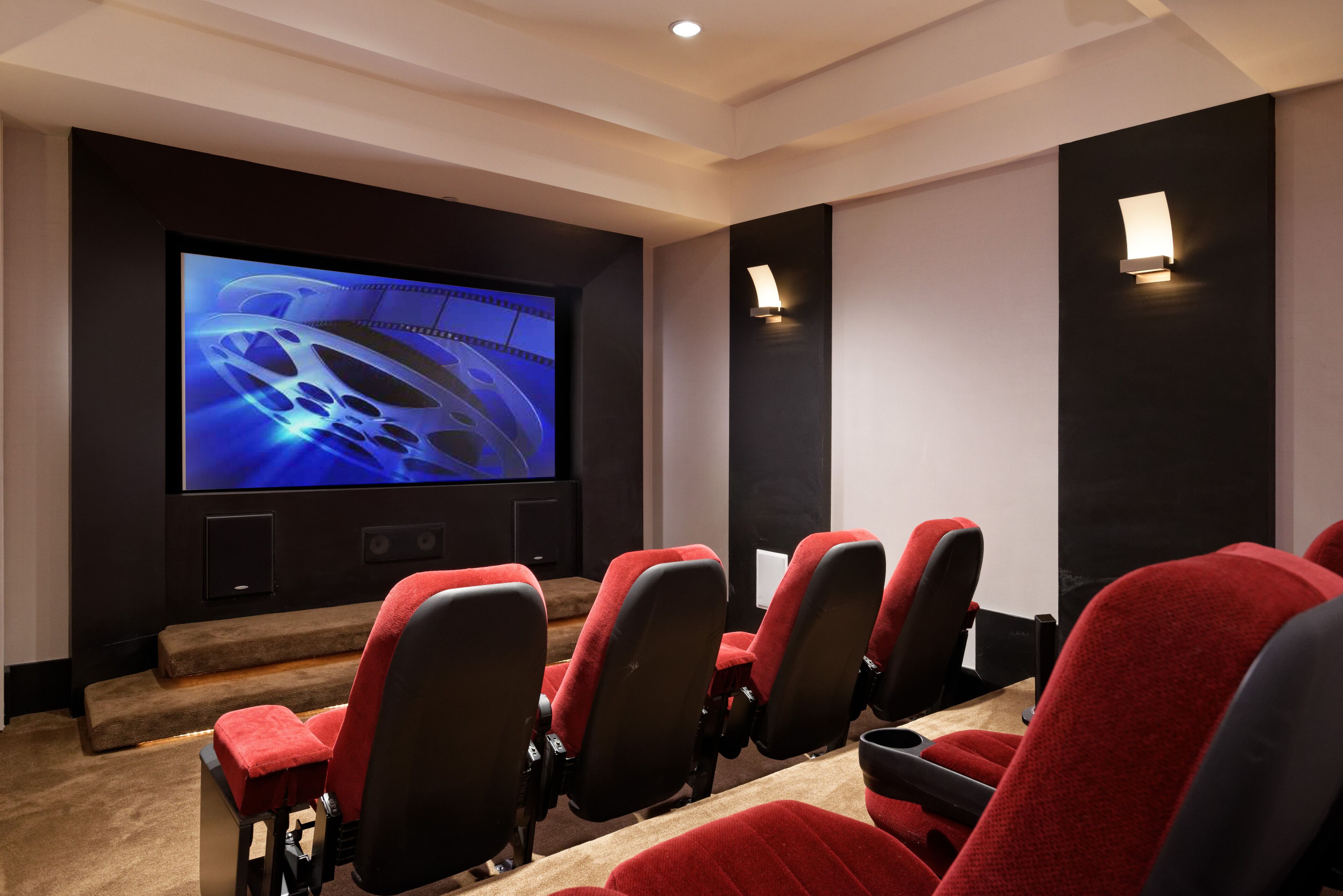 A home theater with a large screen, red seating, and a dark wall design.