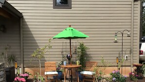 A patio with a table and chairs, surrounded by potted plants and stepping stones. - Close-Country Retreat (Eugene)