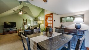 A dining area with a wooden table, chairs, a ceiling fan, and a television in the background. - Close-Country Retreat (Eugene)