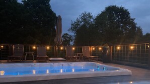 A hot tub area with a wooden deck, lounge chairs, and string lights. - Secluded Modern space, Mountain Views, all year heated Swim Spa & Hot Tub (Trion)