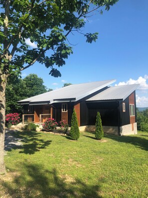 A modern house with a sloped roof, a wooden deck, and a well-maintained lawn.