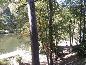 A serene lakeside setting with trees and a wooden dock. -  Charming Waterfront Cabin On The Oconaluftee River in Cherokee NC! (Whittier)