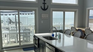 A kitchen with a large island, a view of the beach, and a sign indicating 'The Harkins Family Shore House'. - 4 Br, 2 Ba Penthouse Condo with Ocean View- Beach Block- Heart of Sea Isle City (Sea Isle City)
