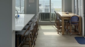 A spacious kitchen with a large island, wooden flooring, and a view of the sea through large windows. - 4 Br, 2 Ba Penthouse Condo with Ocean View- Beach Block- Heart of Sea Isle City (Sea Isle City)