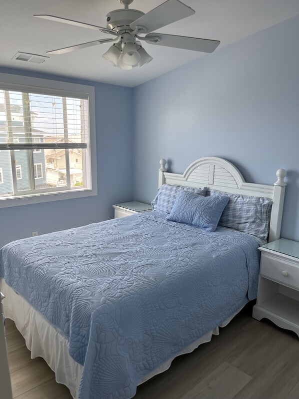 A bedroom with a bed, a nightstand, a ceiling fan, and a window. - 4 Br, 2 Ba Penthouse Condo with Ocean View- Beach Block- Heart of Sea Isle City (Sea Isle City)
