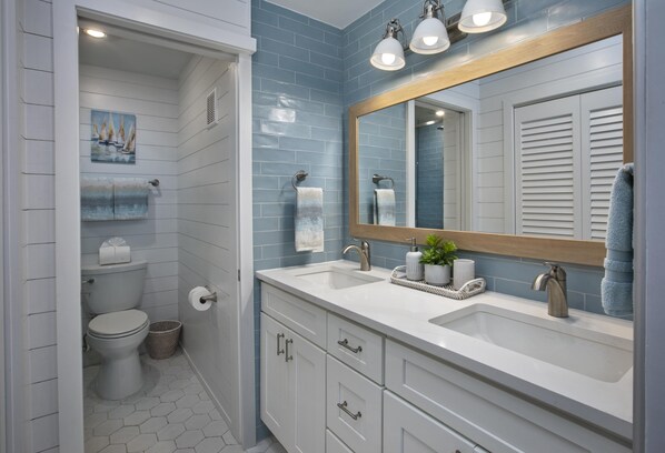 Un baño con un lavabo blanco, un espejo grande y un inodoro.