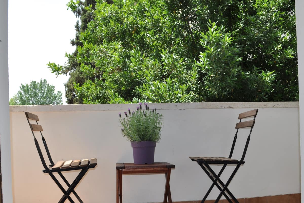 Two foldable chairs with a small table and a potted plant between them on a tiled patio.