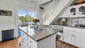 A kitchen with white cabinetry, a granite countertop, and a view to the outdoors.