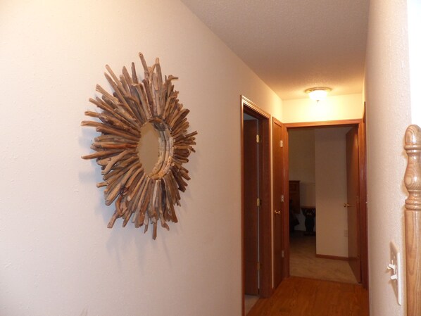 Un pasillo con una puerta de madera y un espejo en la pared.