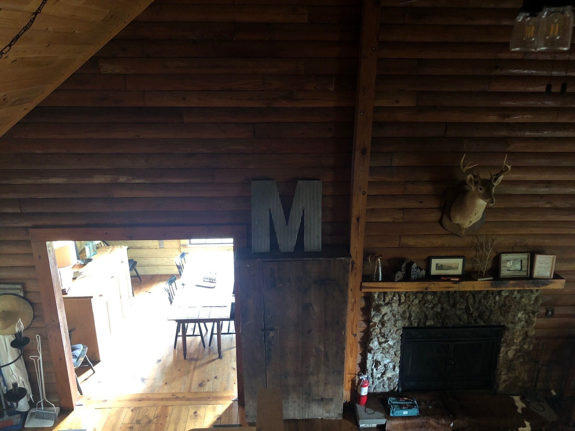 A rustic interior with wooden walls, a stone fireplace, and a mounted deer head.