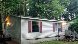 A single-story mobile home with a front porch and a small deck.