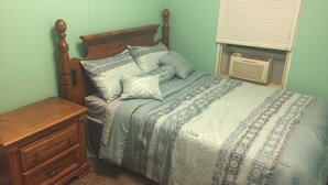 A bedroom with a wooden bed, a nightstand, and a window with blinds.