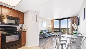 Una cocina moderna con microondas y horno, un comedor con mesa y sillas, y un balcón con vistas.