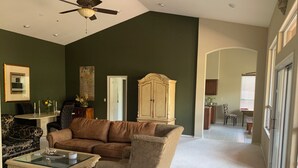 Un salon avec un canapé marron, une table basse en verre, un fauteuil à motifs et un meuble en bois.