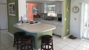 A kitchen with a central island, bar stools, a clock, and a turtle on the floor.