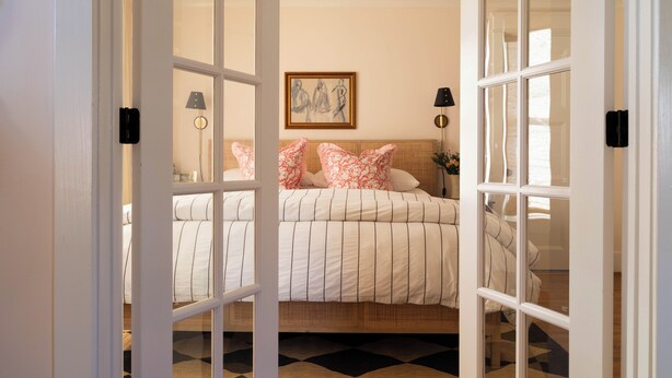 Une chambre à coucher avec un lit, un ventilateur de plafond, un tableau et une table de chevet.