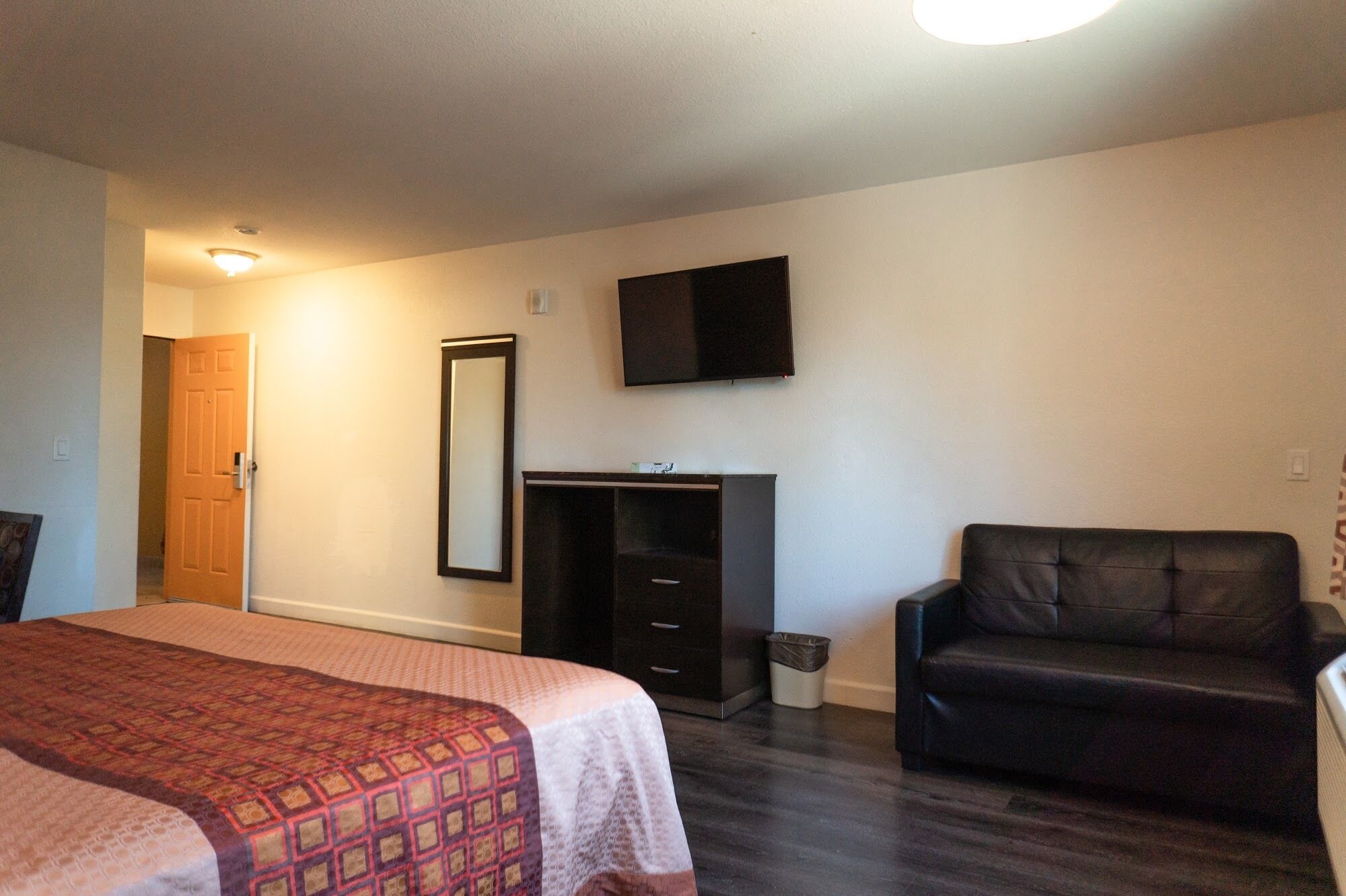 A bedroom with a bed, a dresser, a television, and a chair.